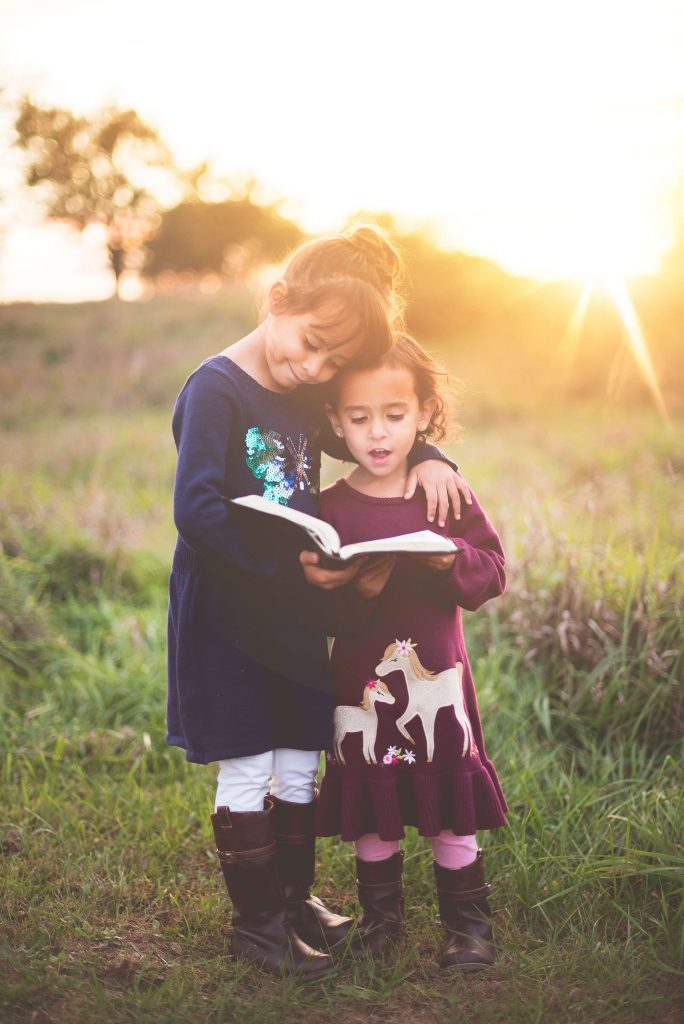 Young girls share a book. Unlock your learner's love for learning with effective NILD educational therapy